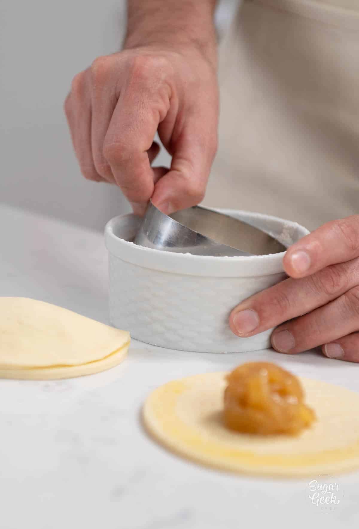 hand dipping a circle cutter in flour. 
