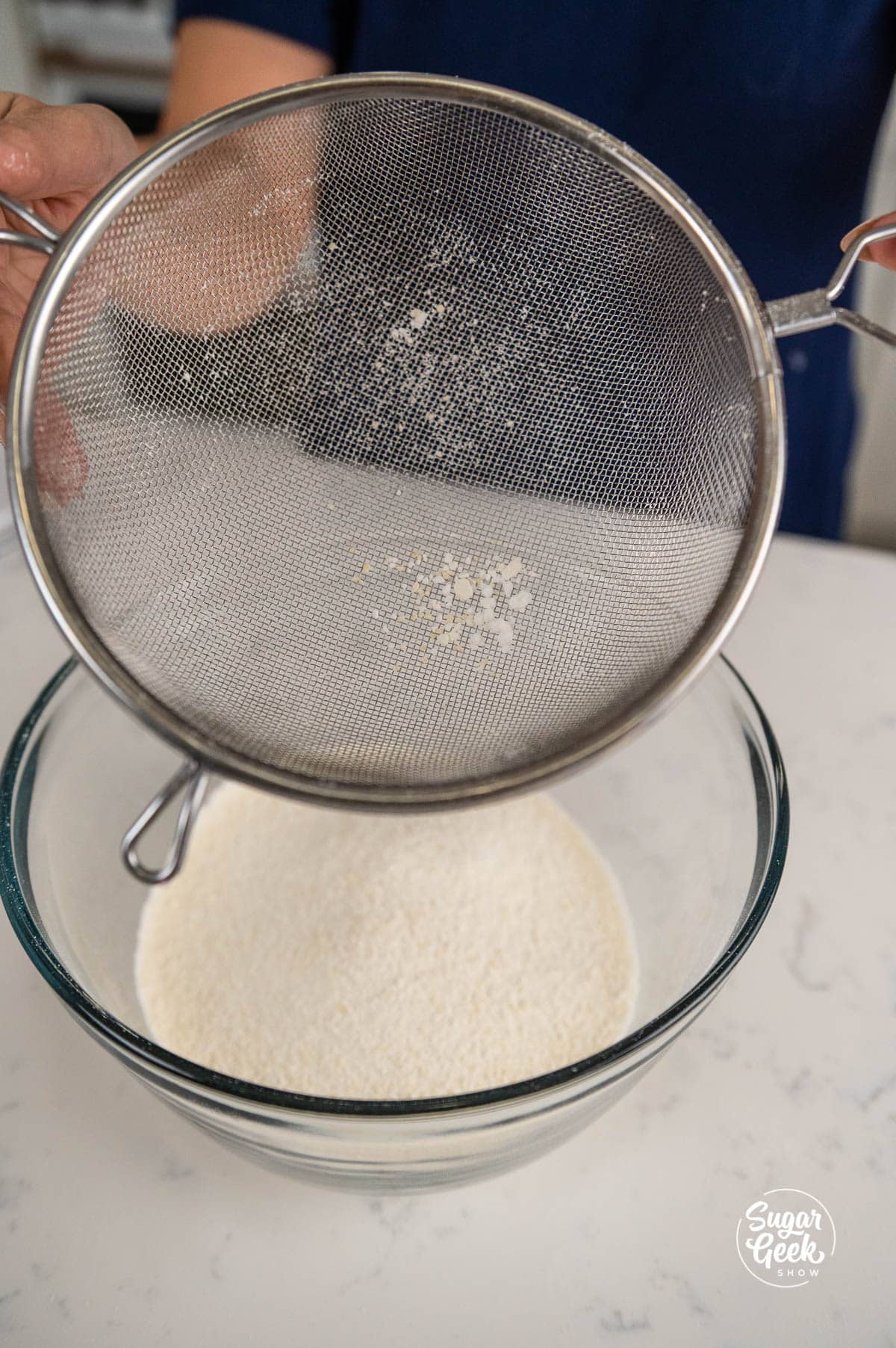 sifting almond flour and powdered sugar into a bowl