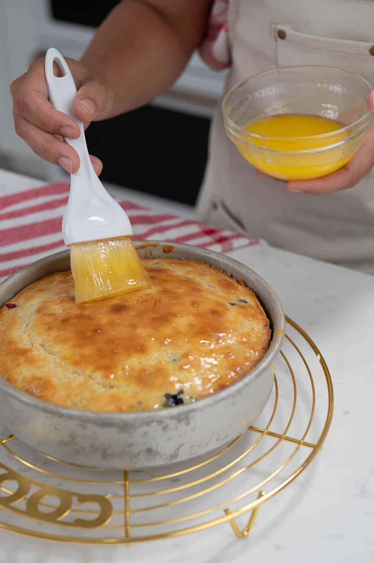 brushing the top of a cake with melted butter