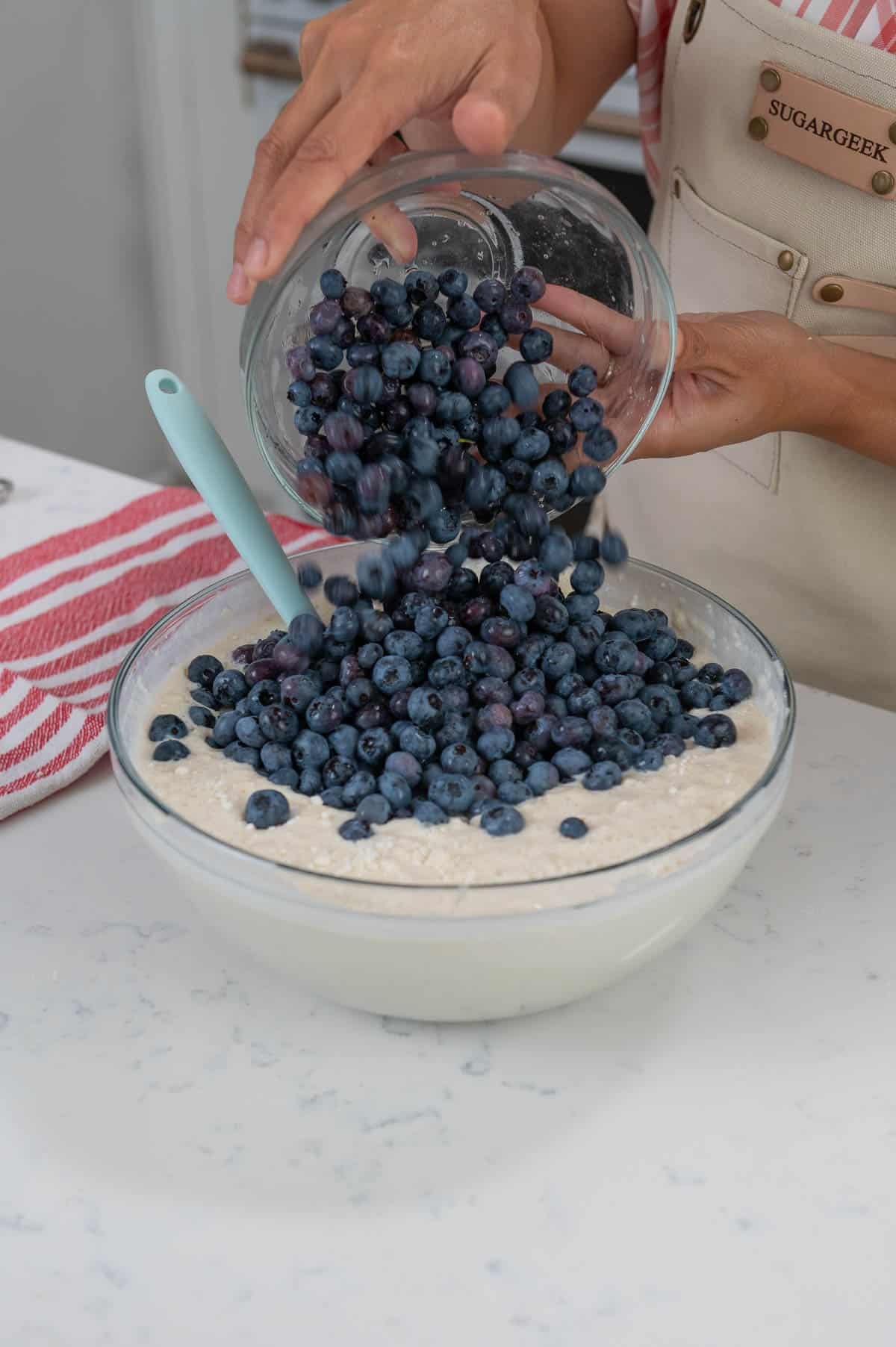adding blueberries to a bowl of pancake mix