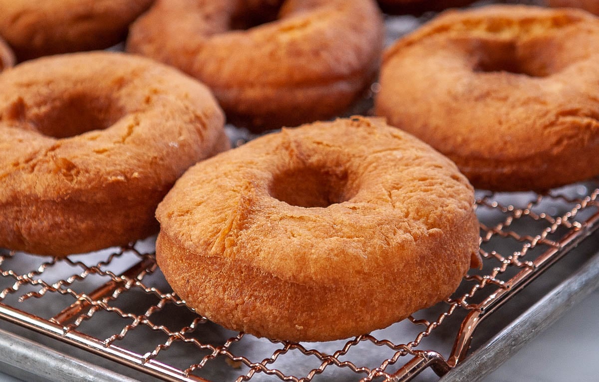 close up of fried cake donuts on a cooling rack
