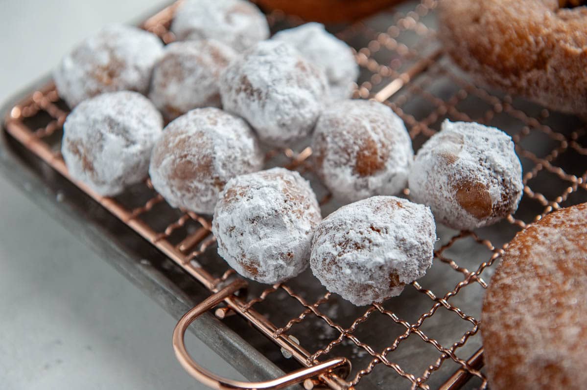 donut holes covered in powdered sugar on a cooling rack