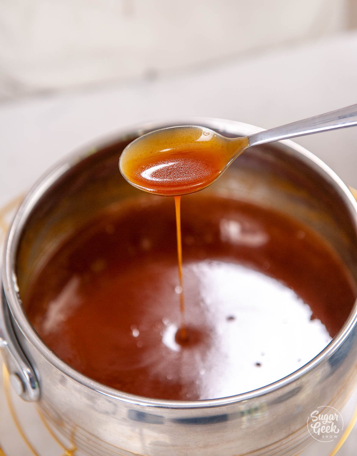 spoon dripping caramel sauce into sauce pan