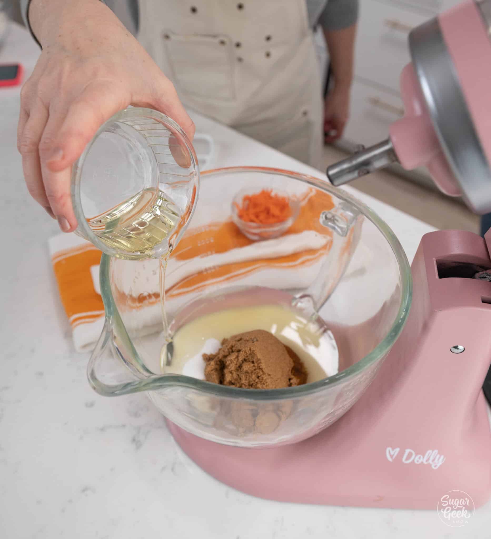 Hand adding oil to a stand mixer bowl