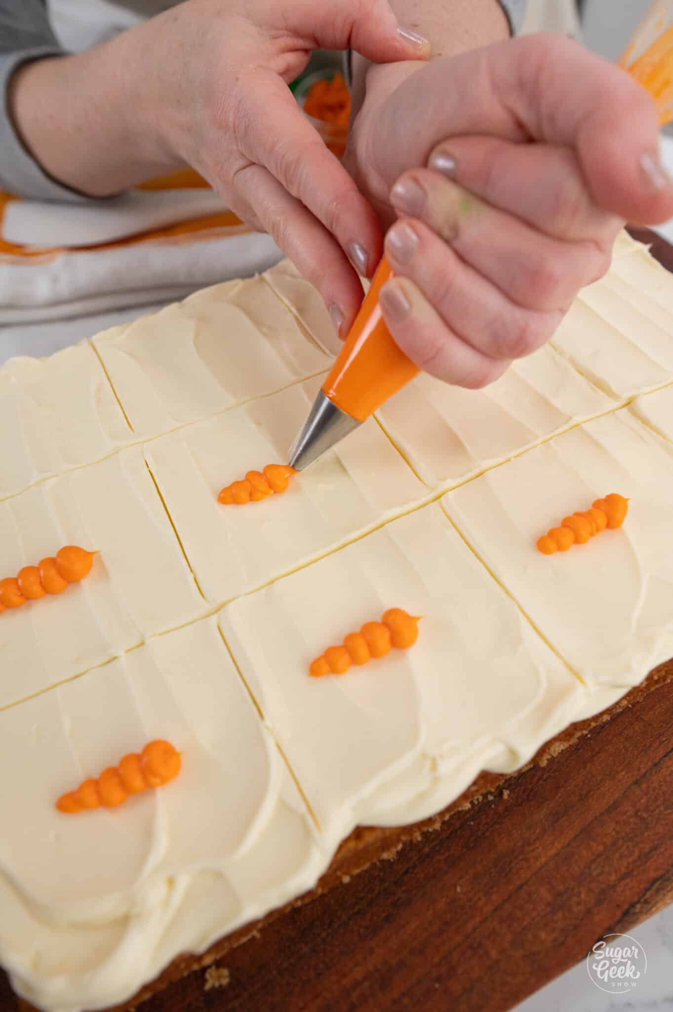 Hand piping a carrot on top of frosting