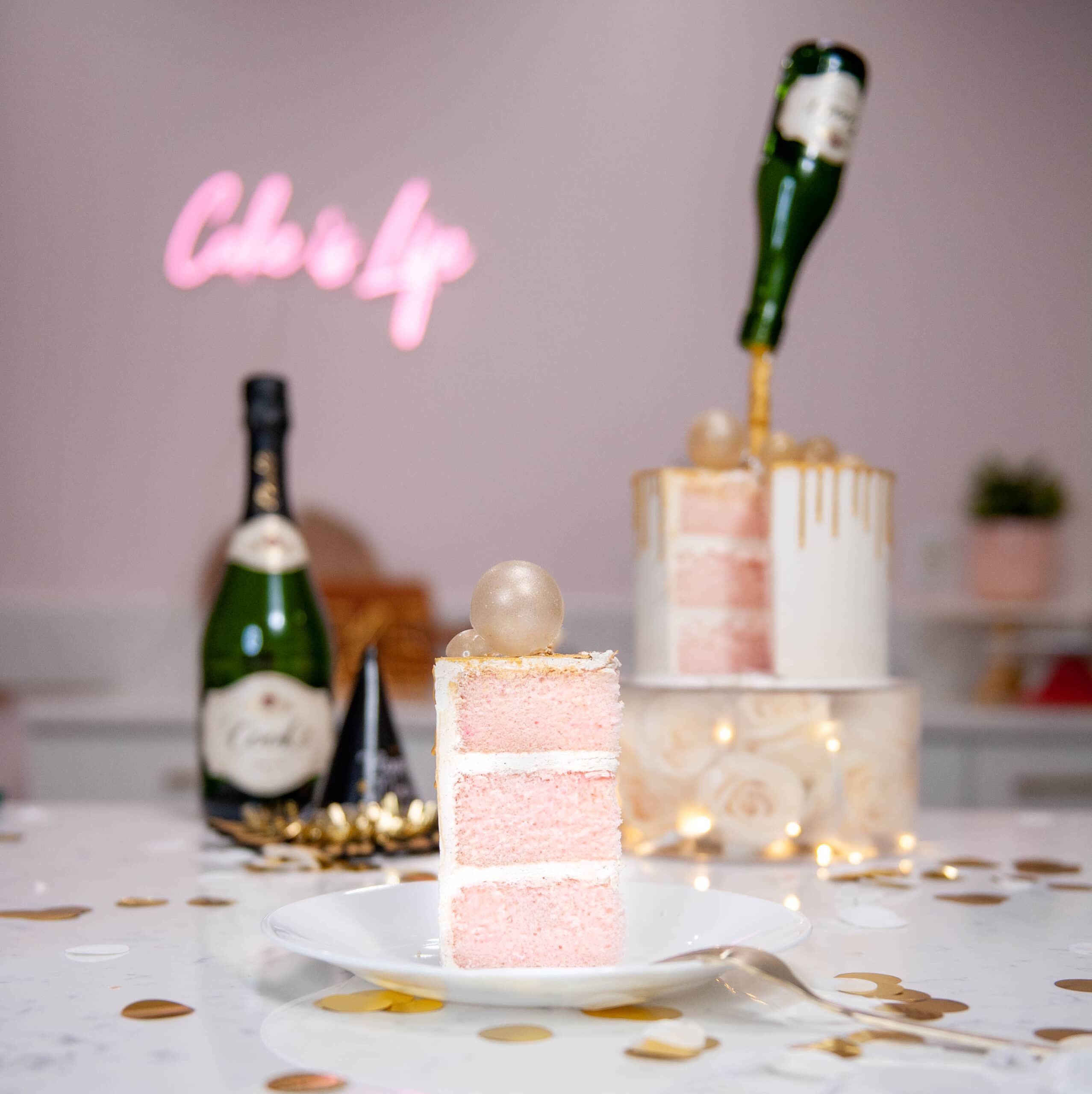 champagne cake on a plate with cake and champagne bottle in the background