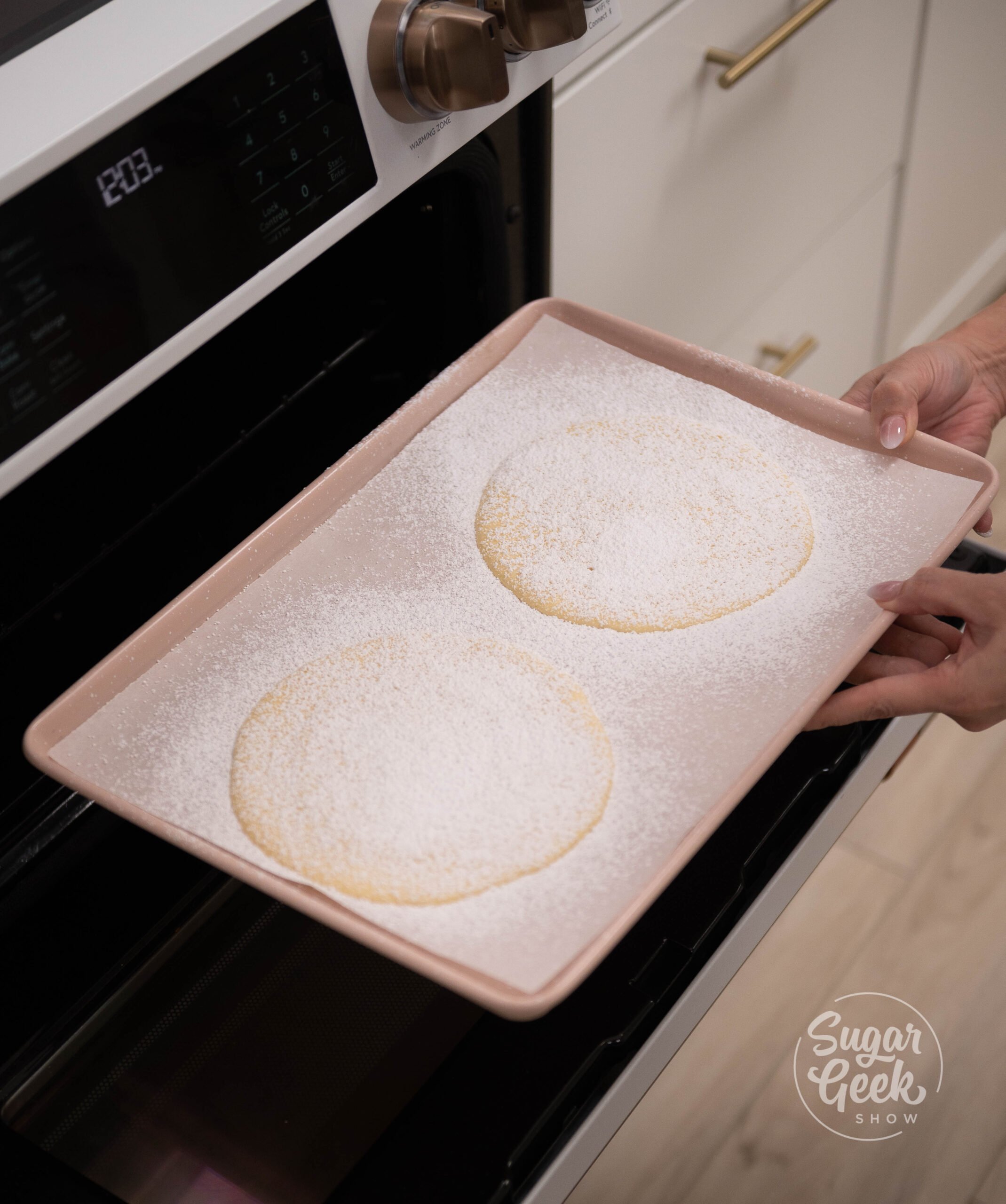 hand placing baking tray of cookies into oven