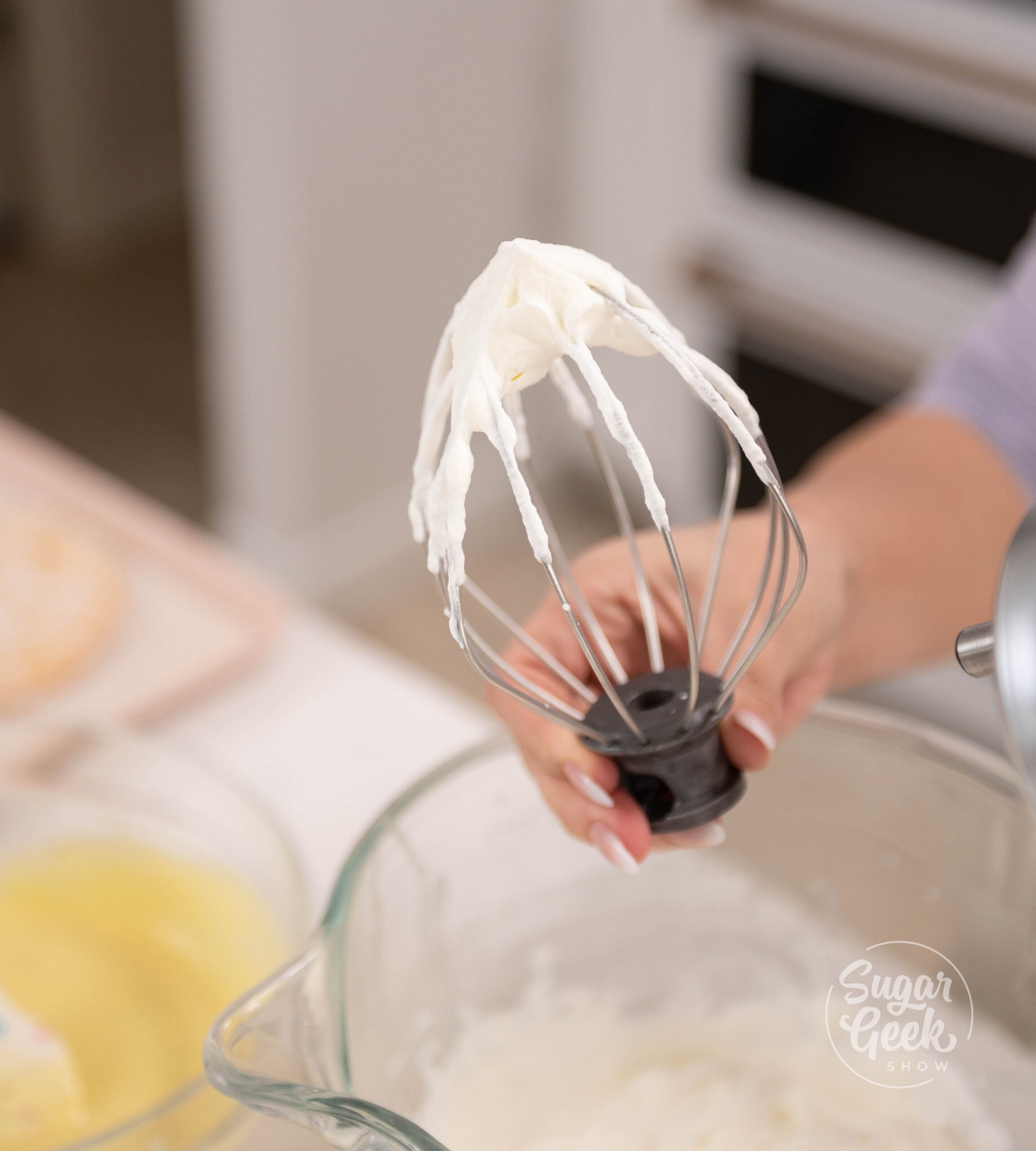 hand holding whisk with whipped cream