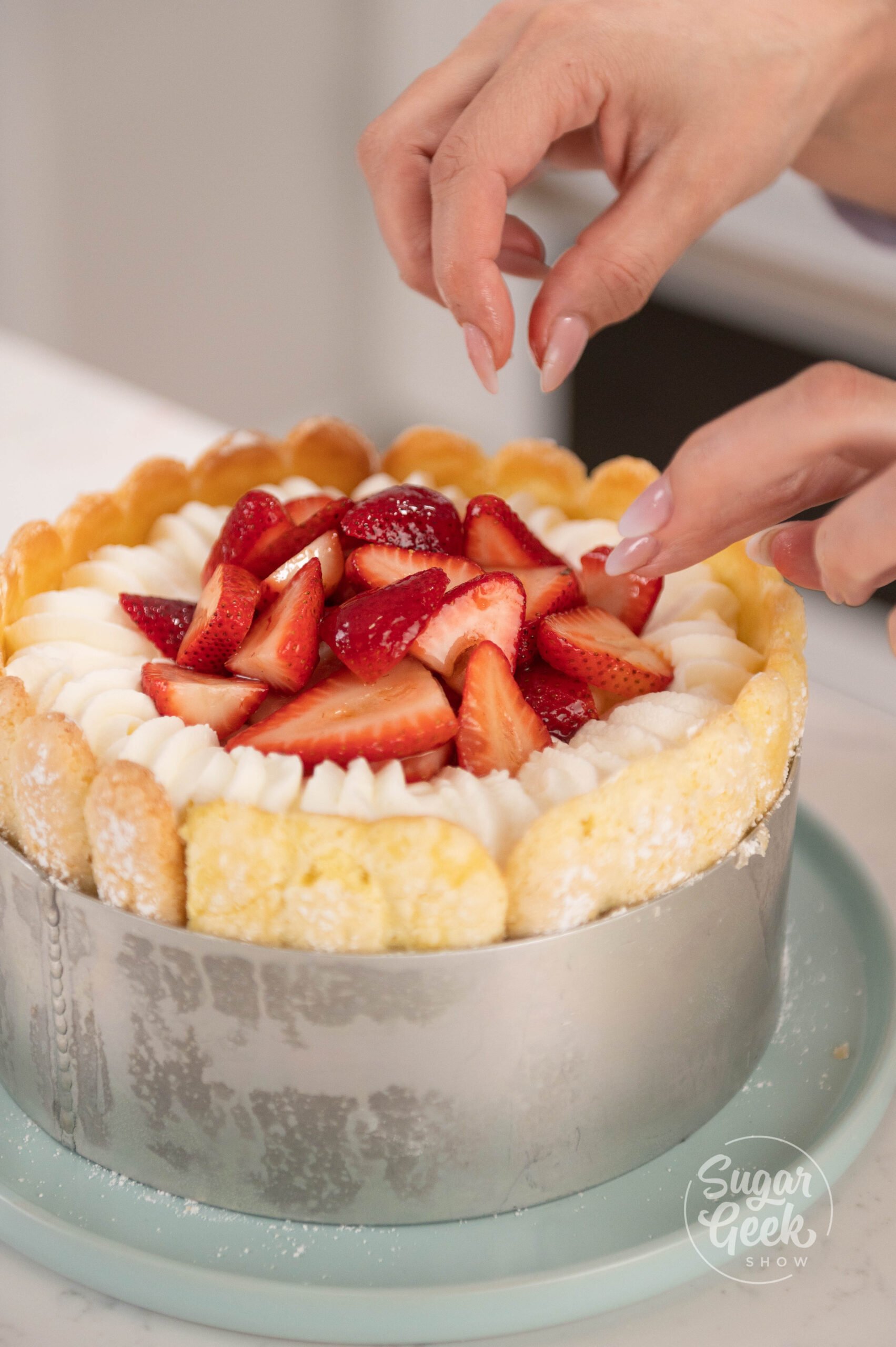 hand placing strawberries on top of cake