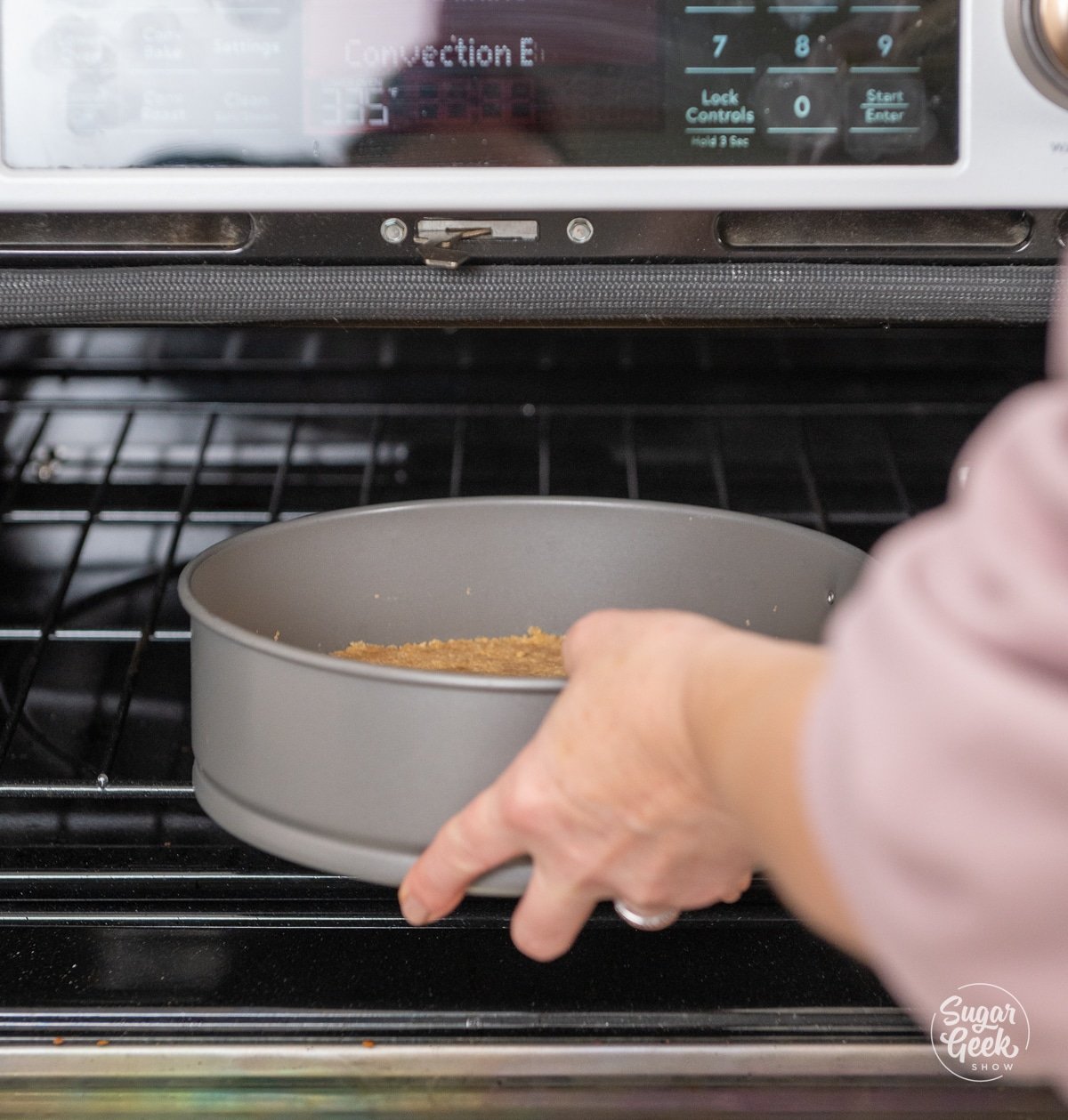 hands placing a springform pan into an oven