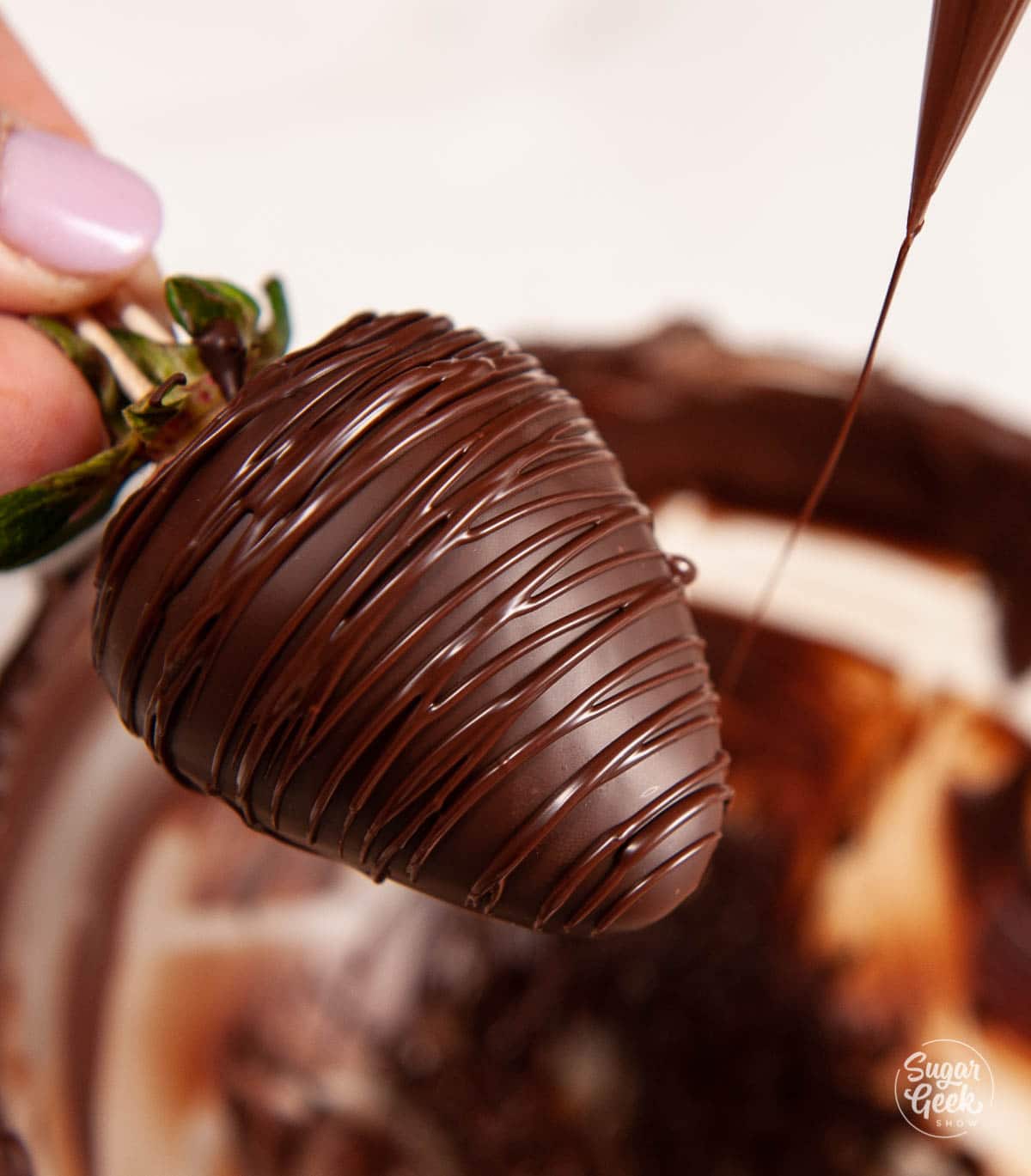 drizzling chocolate over a chocolate covered strawberry