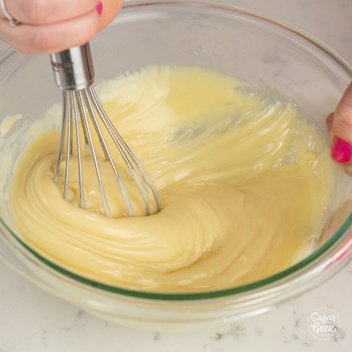 whisk mixing together white chocolate ganache in a bowl