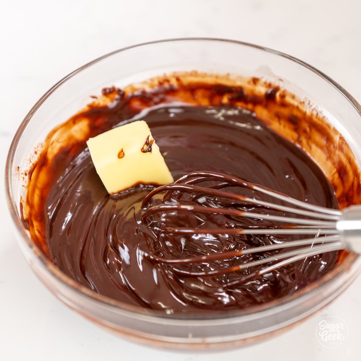 cube of butter in a bowl of dark chocolate ganache