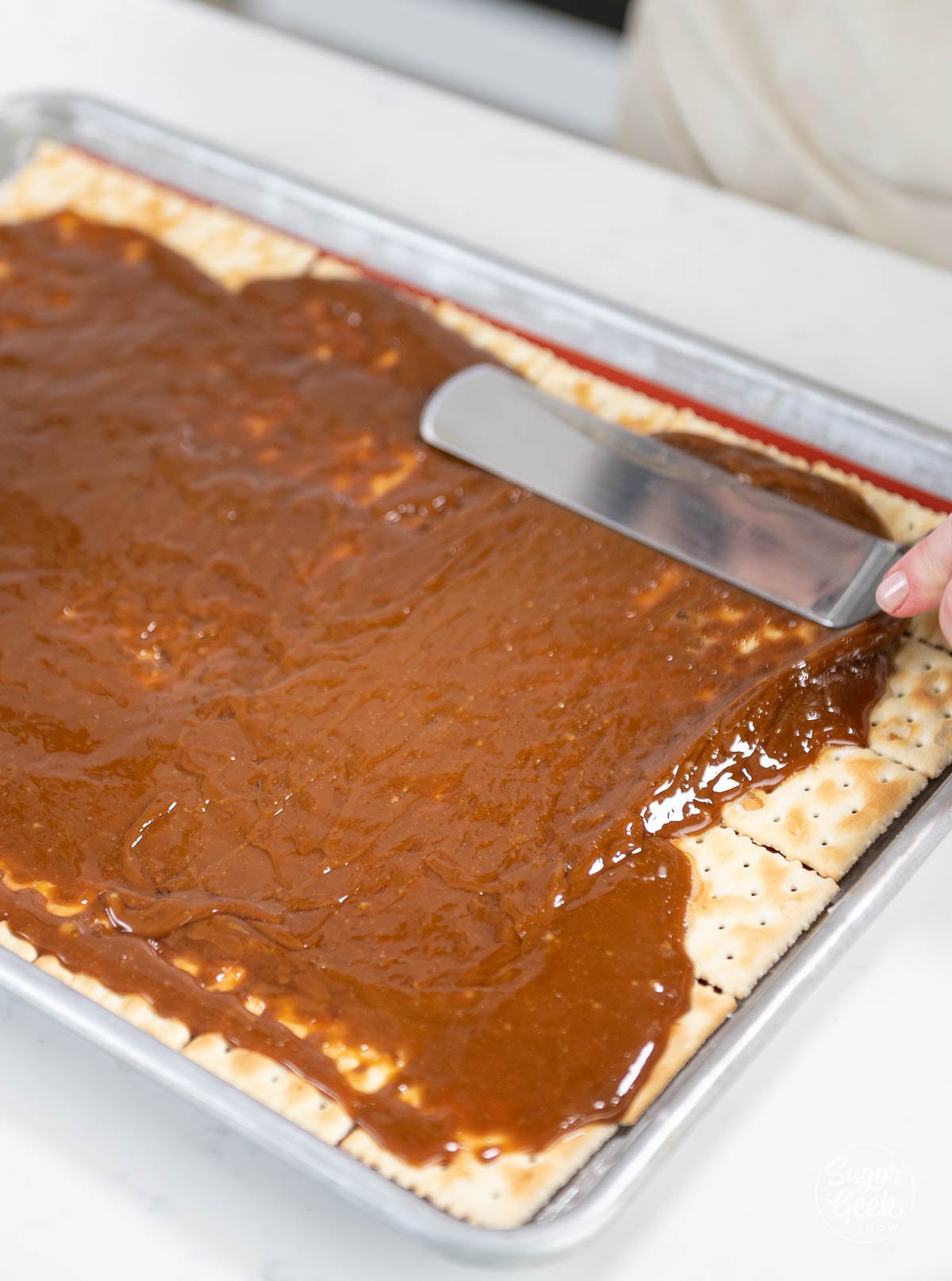 smoothing toffee over saltine crackers