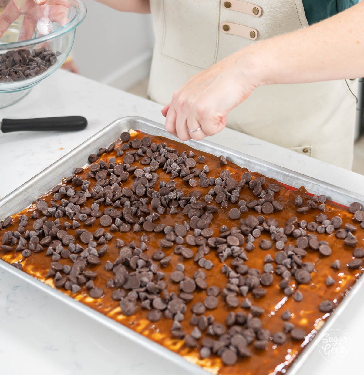 sprinkling chocolate chips onto crackers and toffee