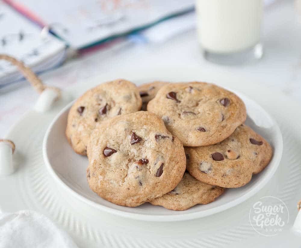 classic chocolate chip cookies in a white bowl on a white background with school book and milk in the background