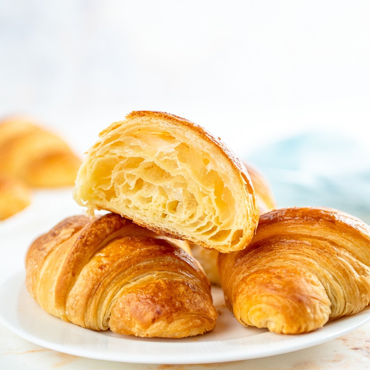 half open croissant laying on top of two other croissants on a plate