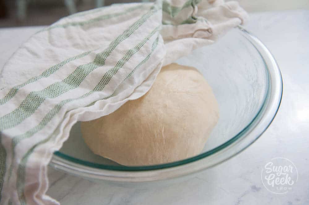 putting bread dough in a lightly greased bowl and covering with a towel to proof