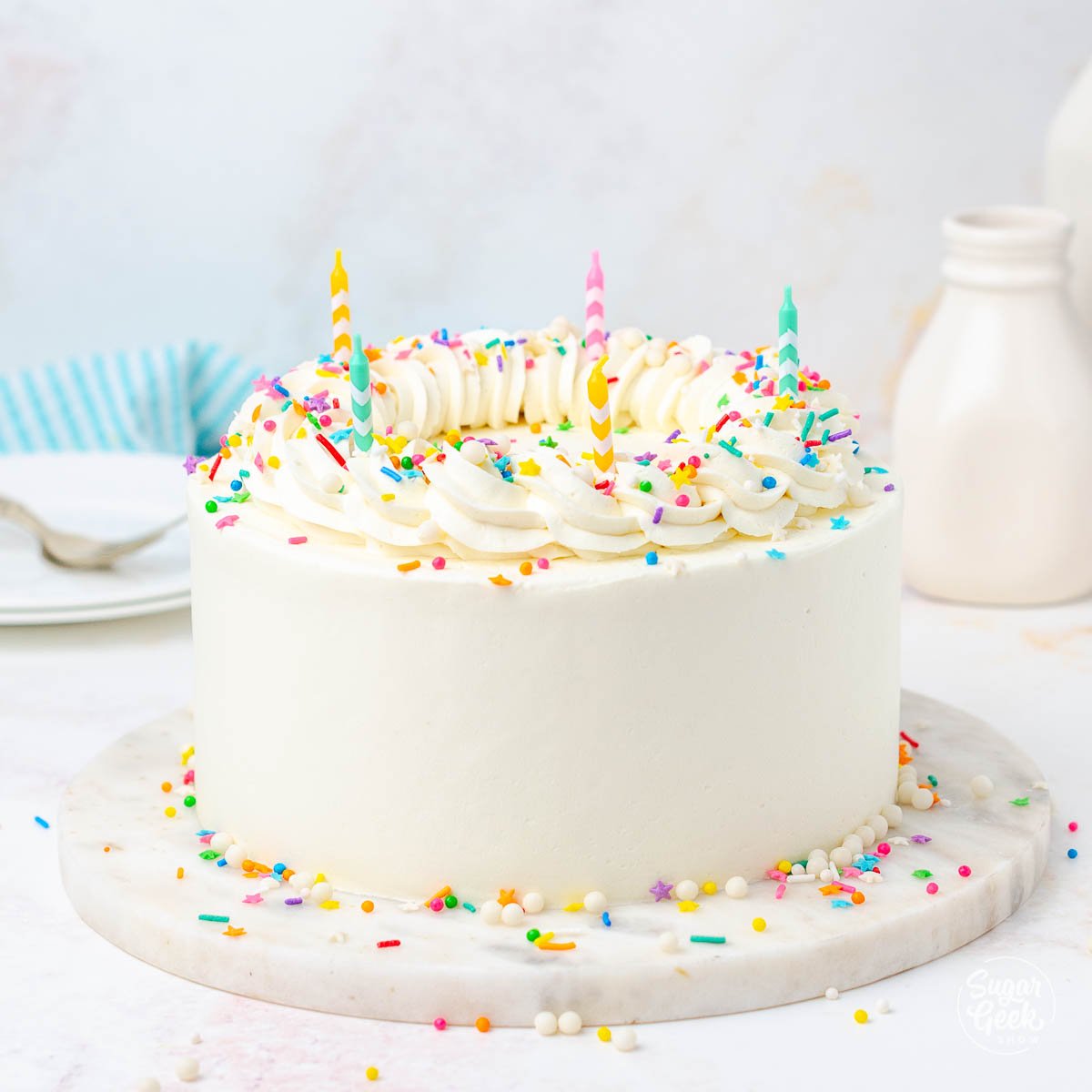 closeup of cake with white frosting and colorful sprinkles