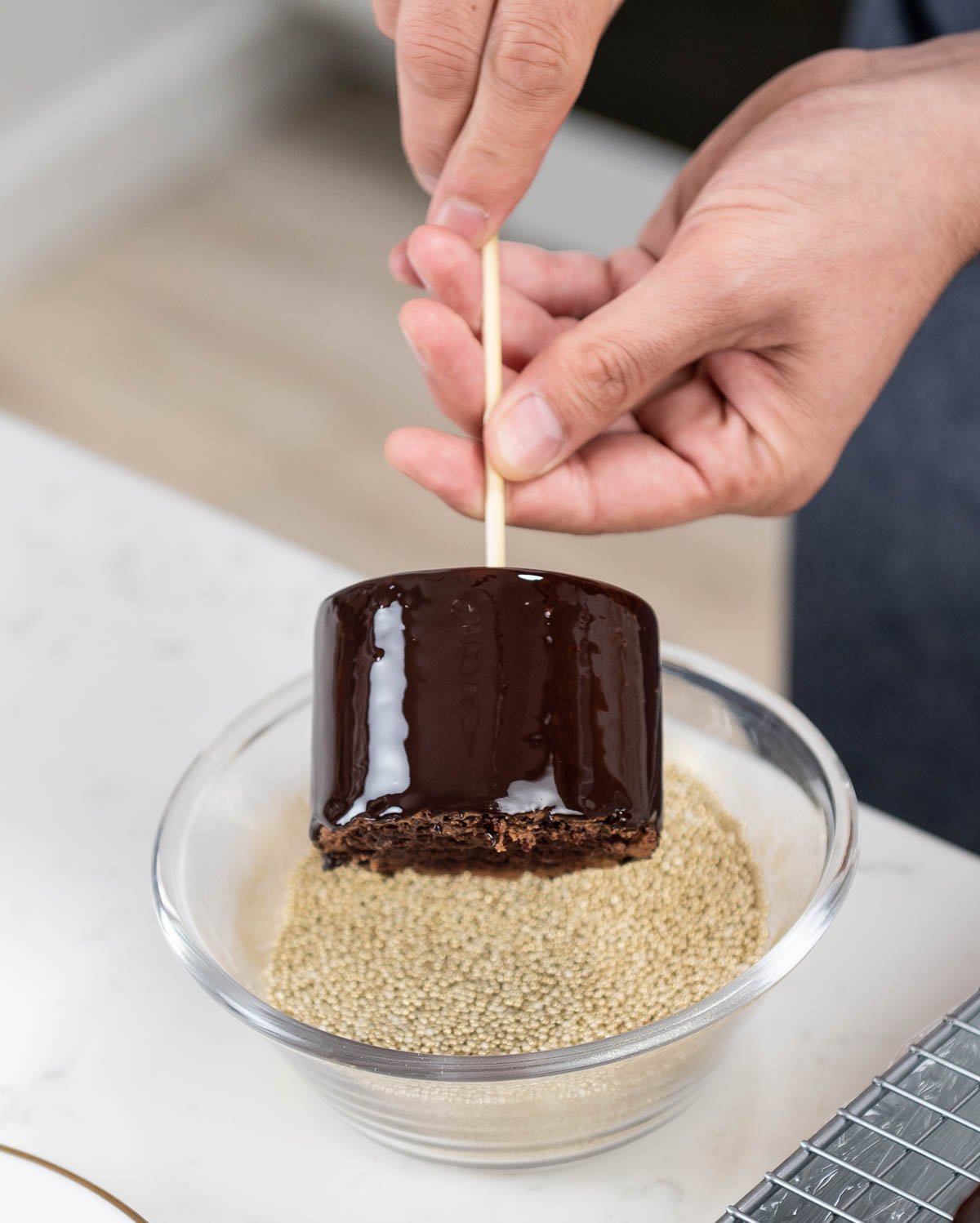 hand rolling chocolate entremet in bowl of edible gold sprinkles
