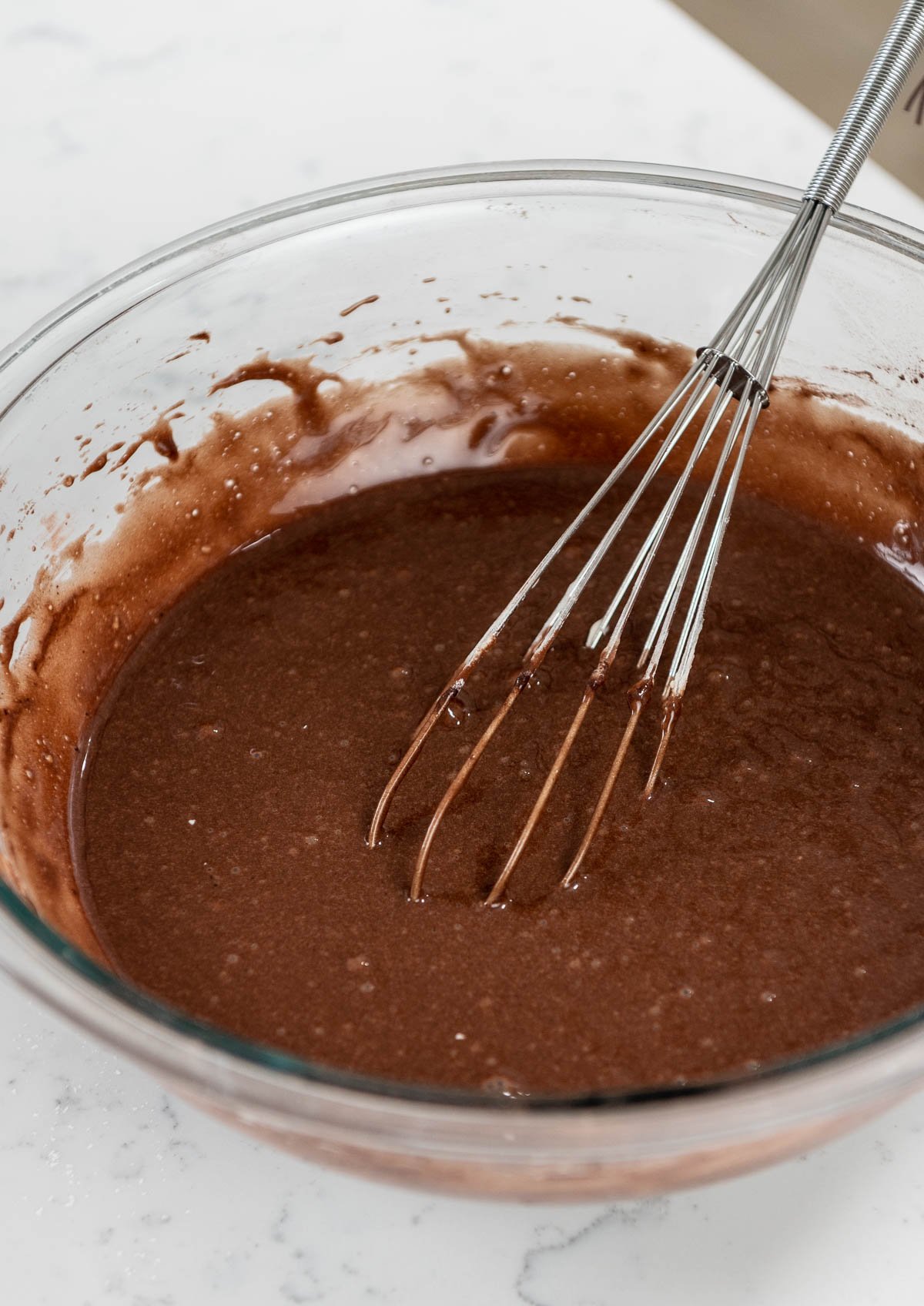 whisk inside bowl of chocolate batter