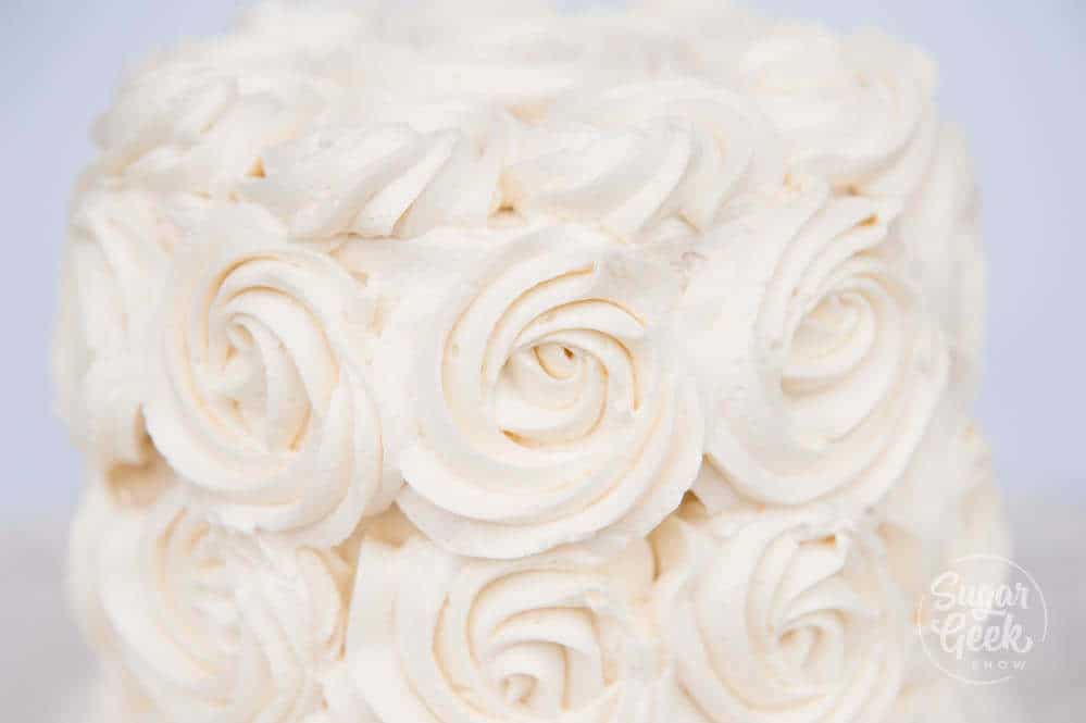 ermine frosting piped into rosettes on a cake