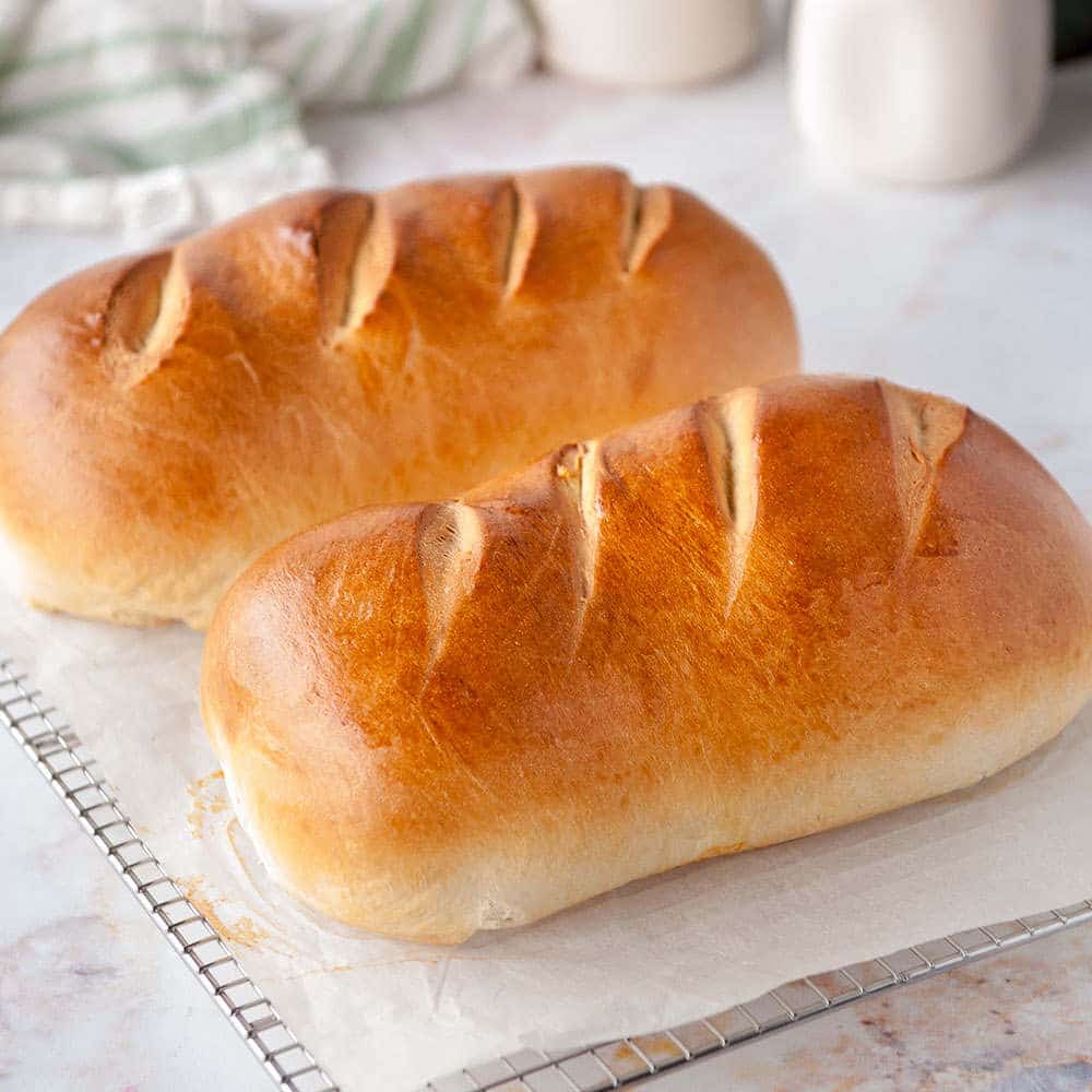 two loaves of homemade bread on cooling a rack on a white background