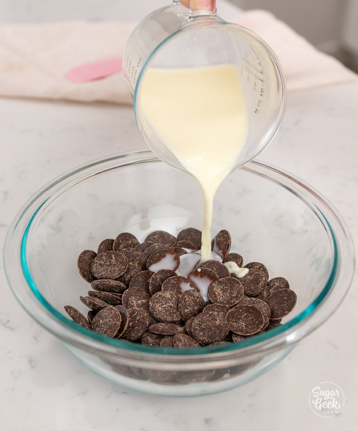hand adding a bowl of hot cream to dark chocolate