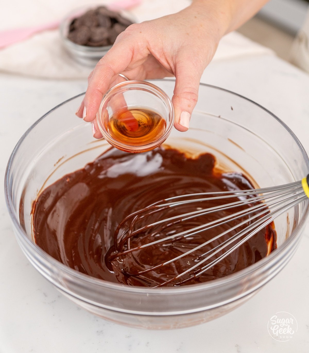 hand adding liquor into a bowl of melted chocolate