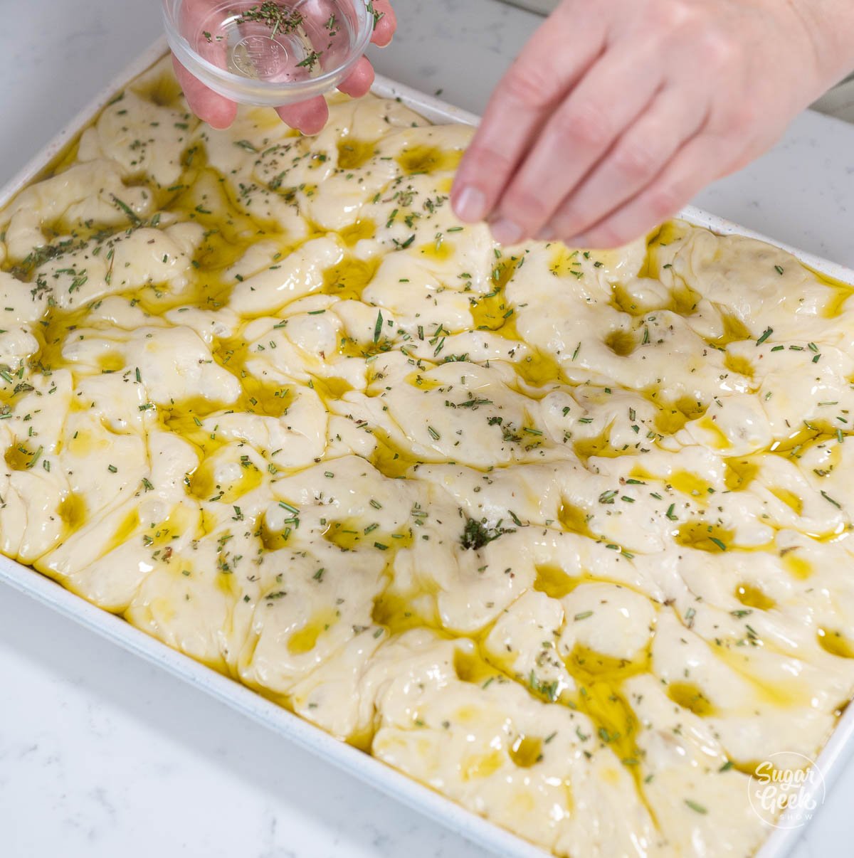 adding rosemary and flakey salt to the top of the focaccia