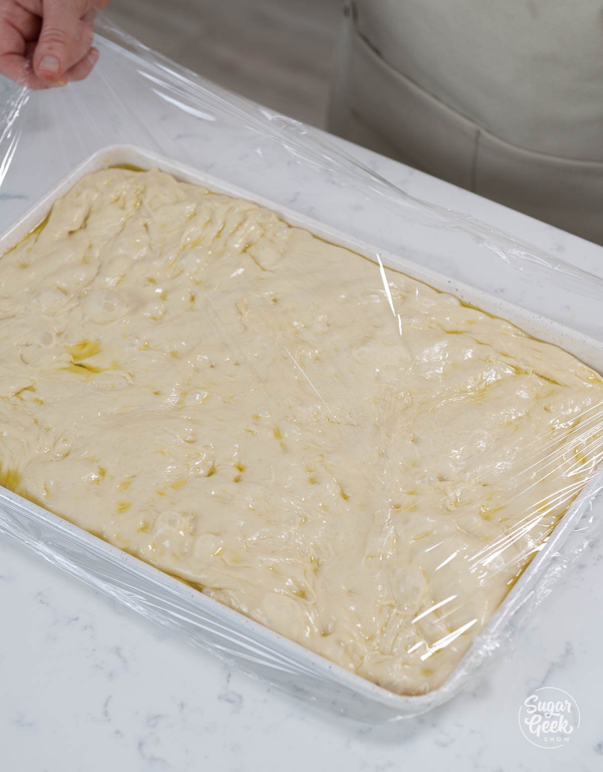 focaccia bread dough covered with plastic wrap