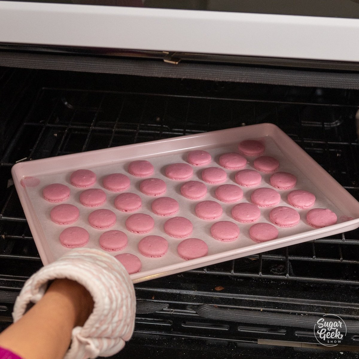 hand in a an oven mitt rotating a baking tray in the oven