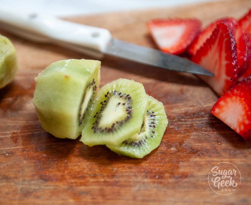 cut kiwi and strawberries on wooden cutting board