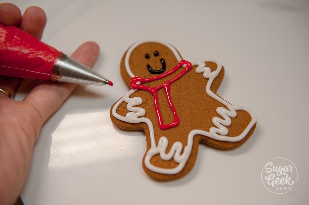 Outline a scarf for the gingerbread man in red royal icing