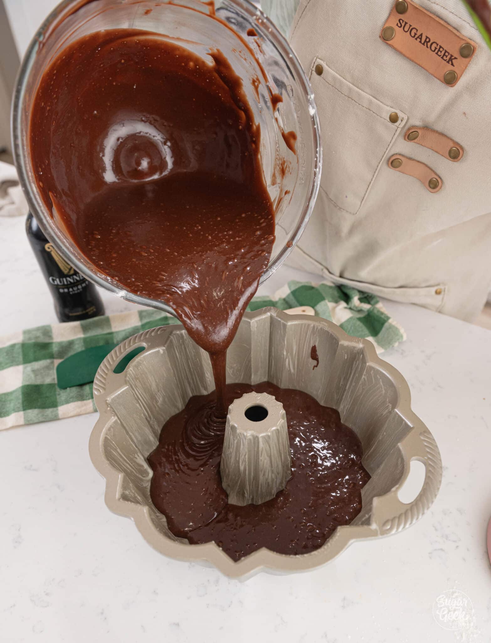 pouring chocolate cake batter from a mixing bowl into a bundt pan
