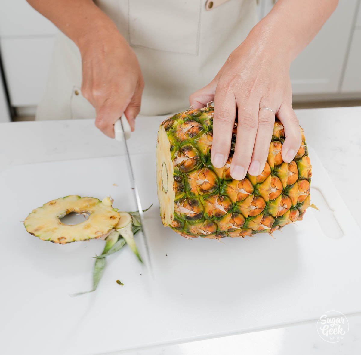 hand using knife to cut pineapple ends