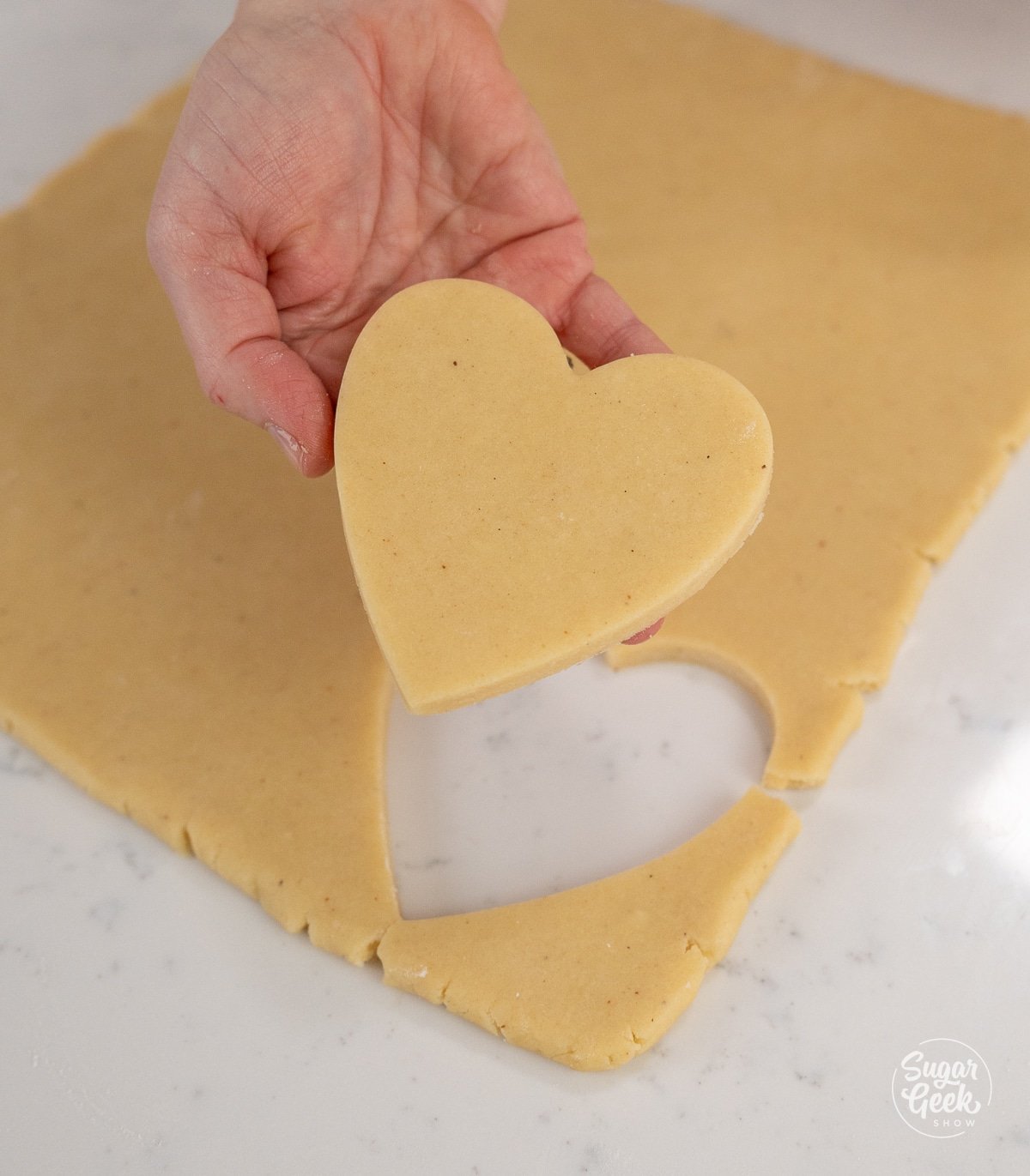 hand holding cut out heart shaped cookies