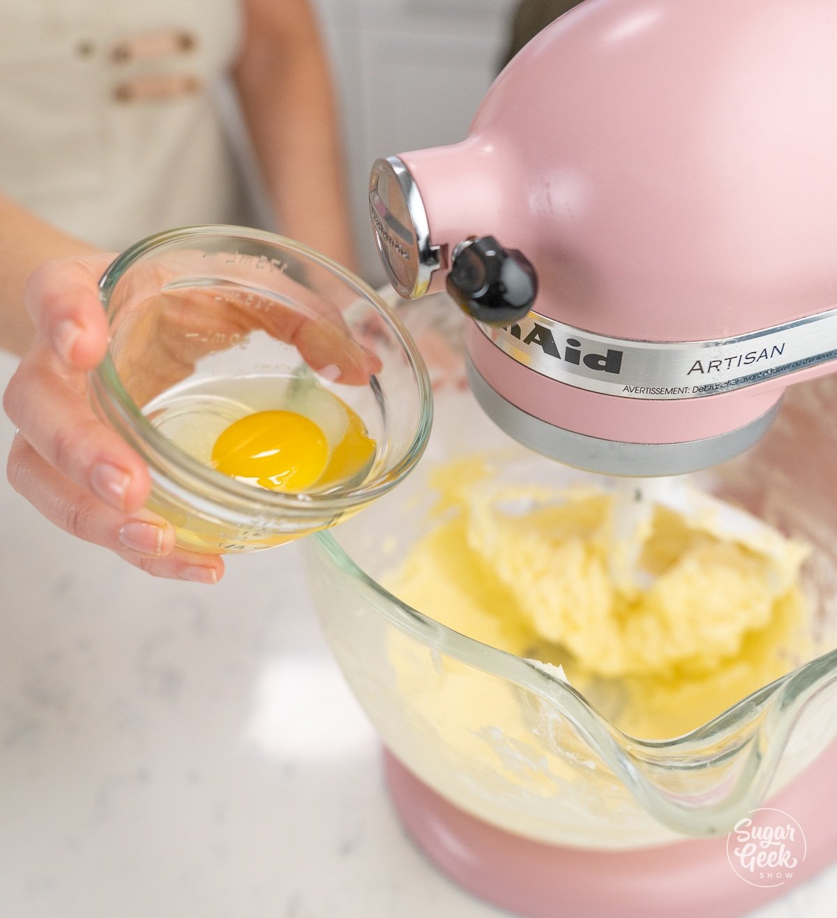 hand adding bowl of eggs into dough mixture.
