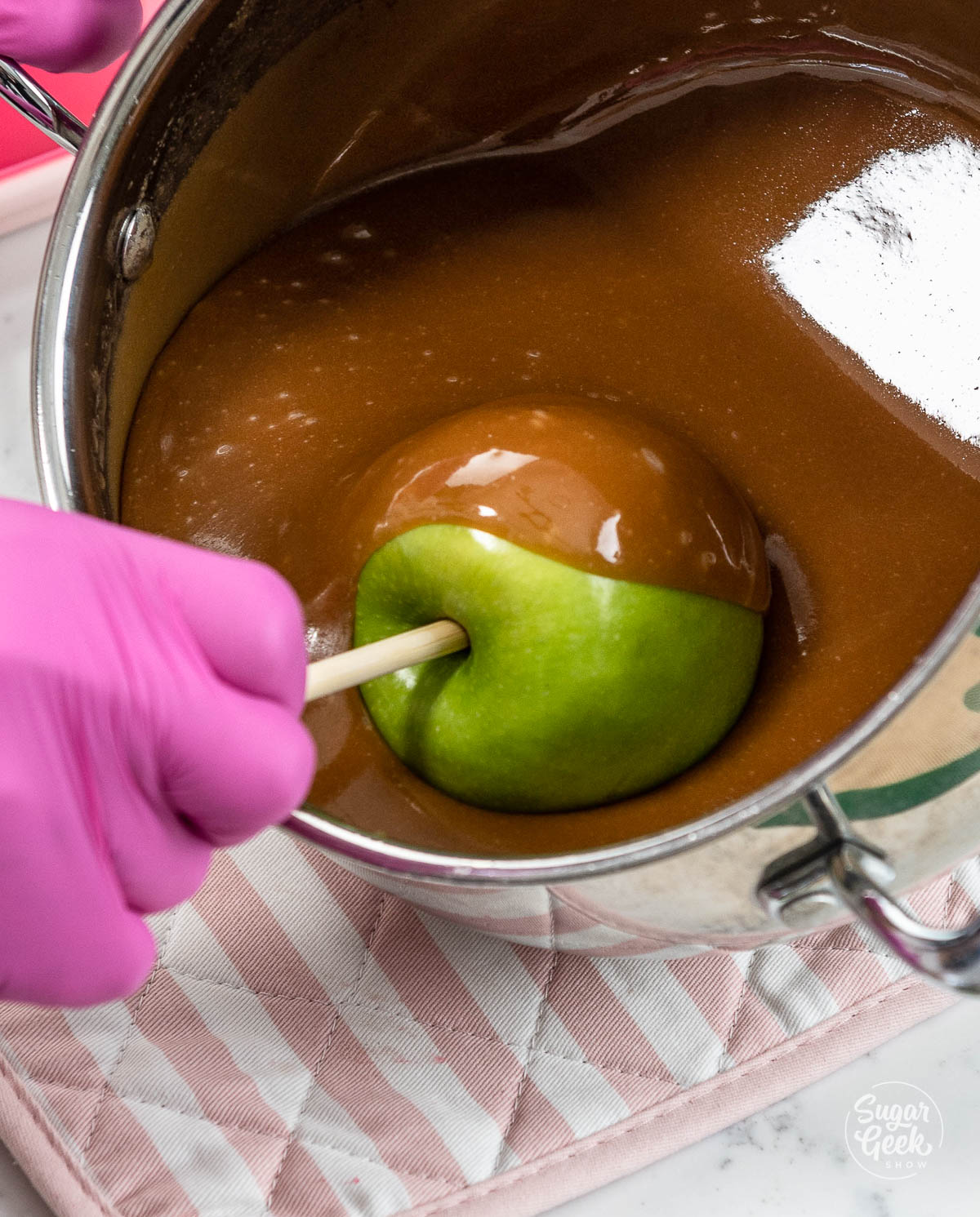 closeup of apple being dipped into caramel