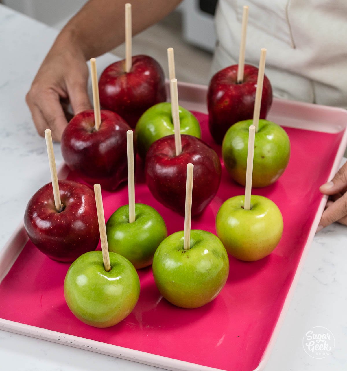 green and red apples on a sheetpan with a pink silicone mat
