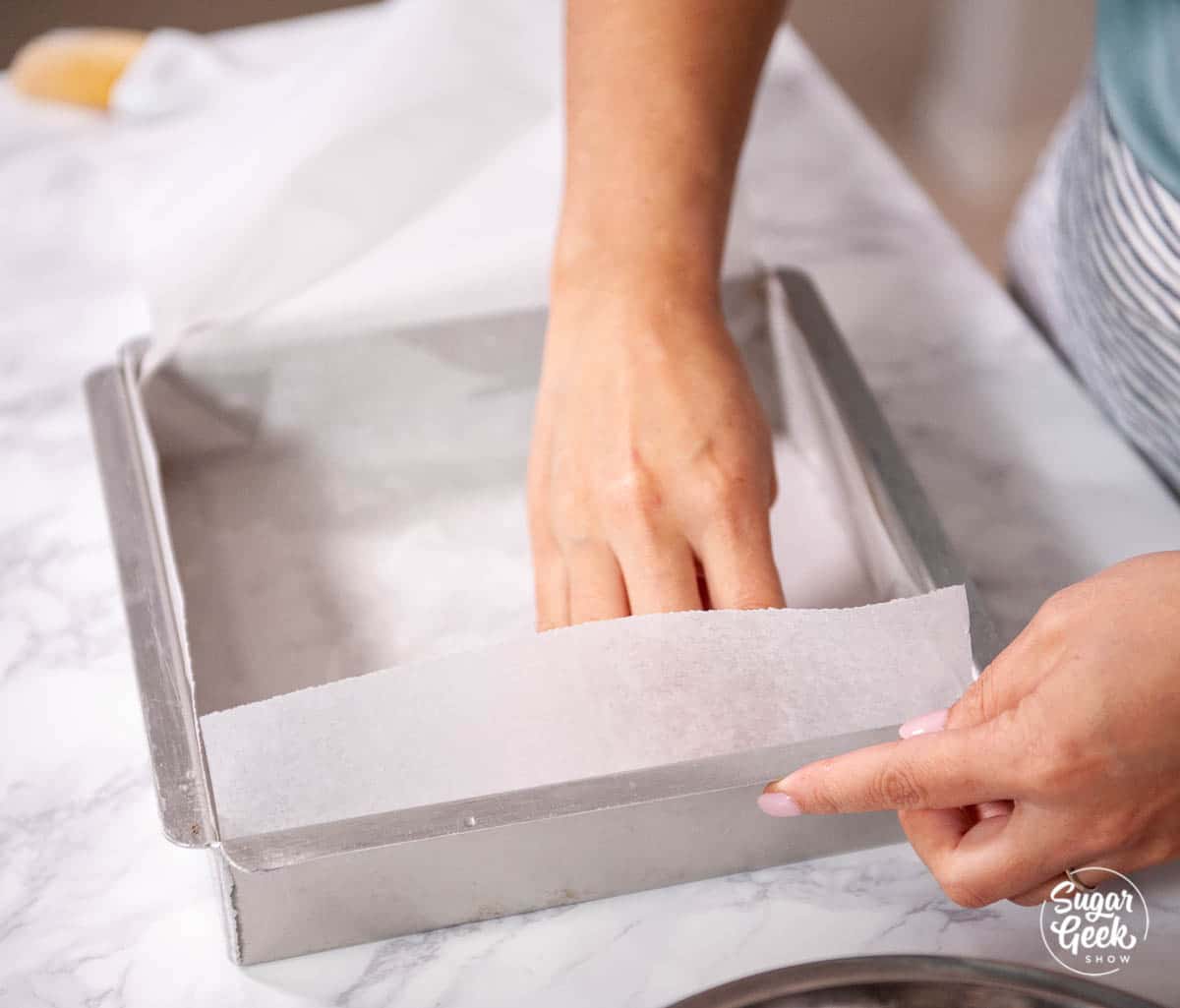 lining a square metal pan with parchment paper
