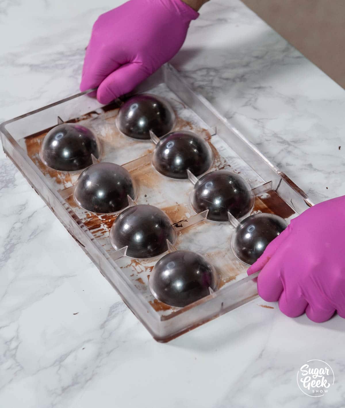 sphere mold with chocolate on a white counter