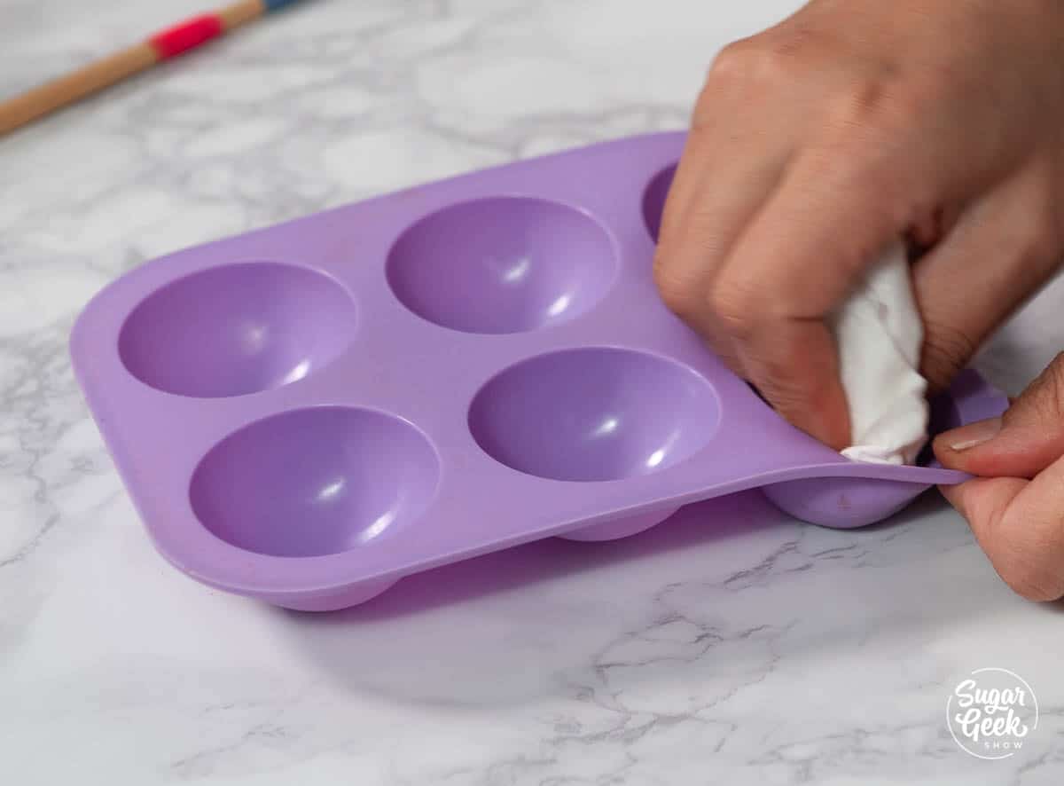 polishing a purple silicone sphere mold with a paper towel