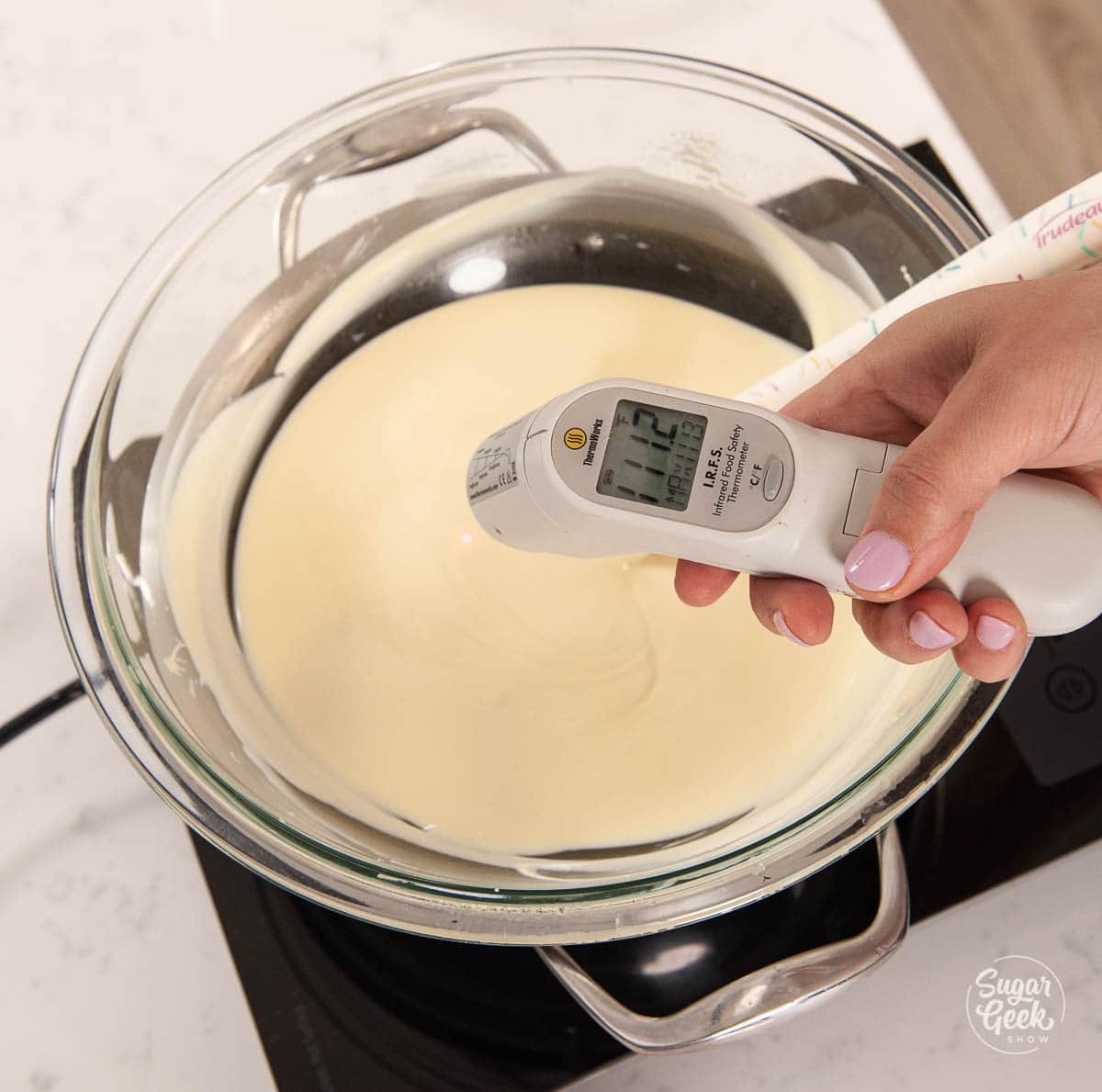 infrared thermometer held in hand over melted chocolate