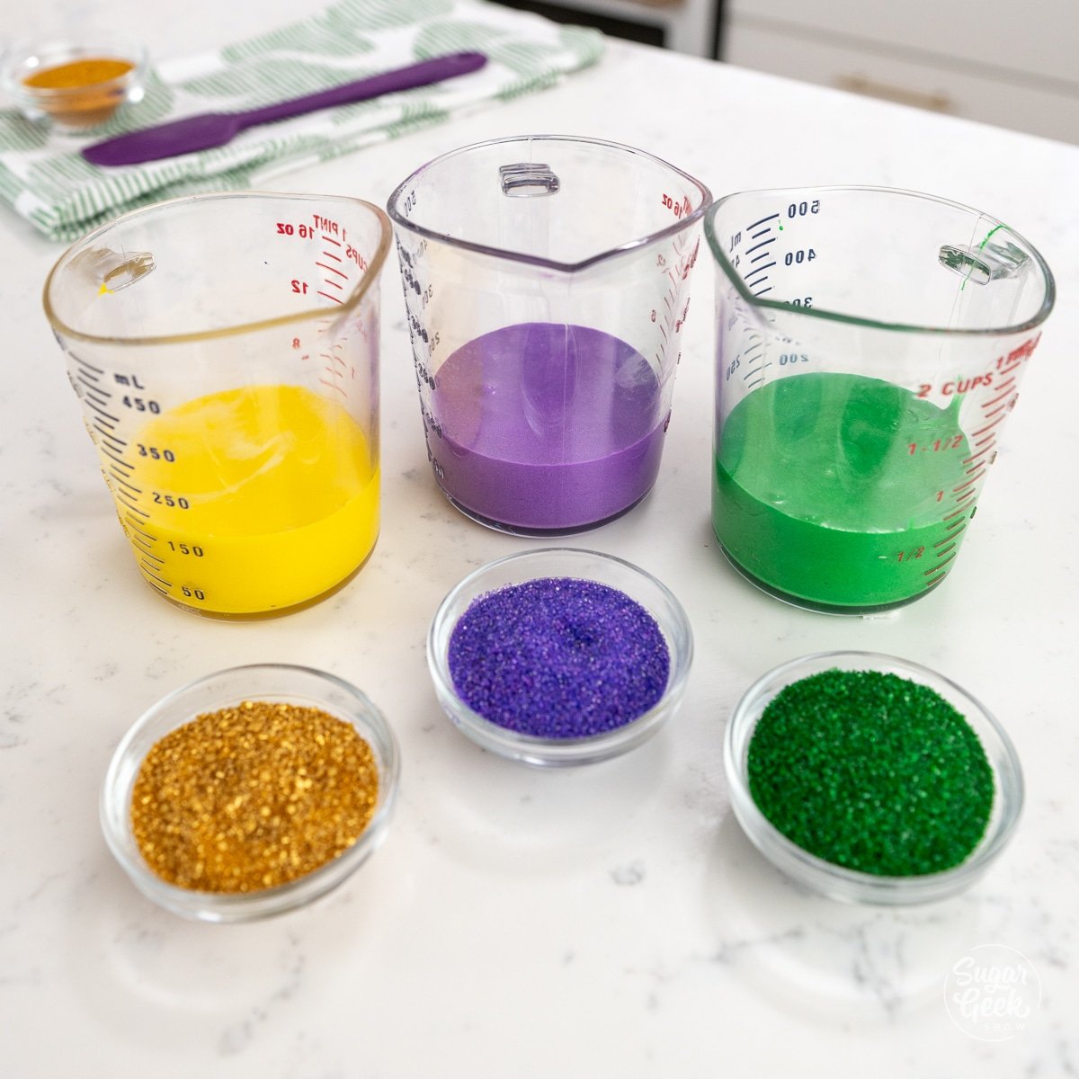 containers of gold, purple, and green glaze and sprinkles