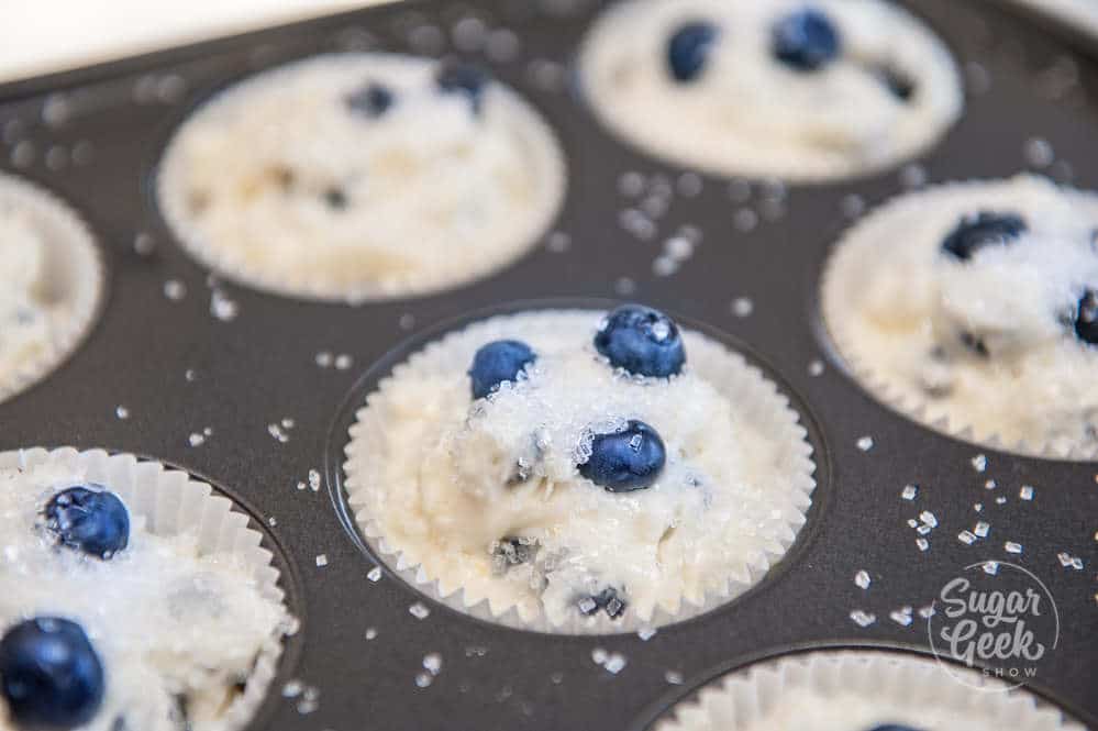 lemon blueberry muffin batter in muffin tin with sparkling sugar on top