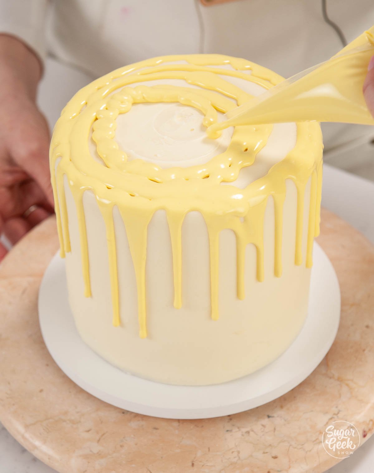adding lemon ganache to the top of a lemon layer cake