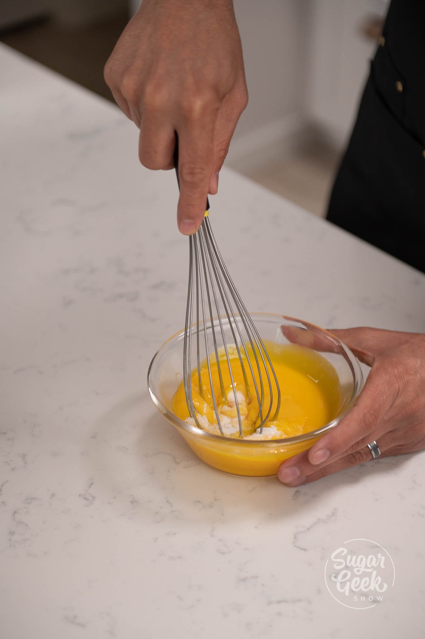 hand using whisk to whisk together yolks and sugar.