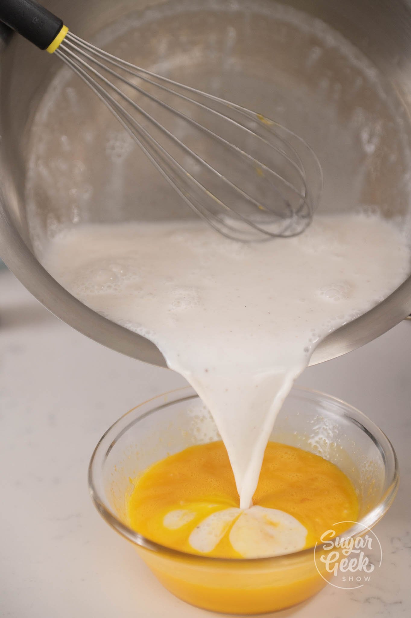 potnof cream being poured into container of yolks.
