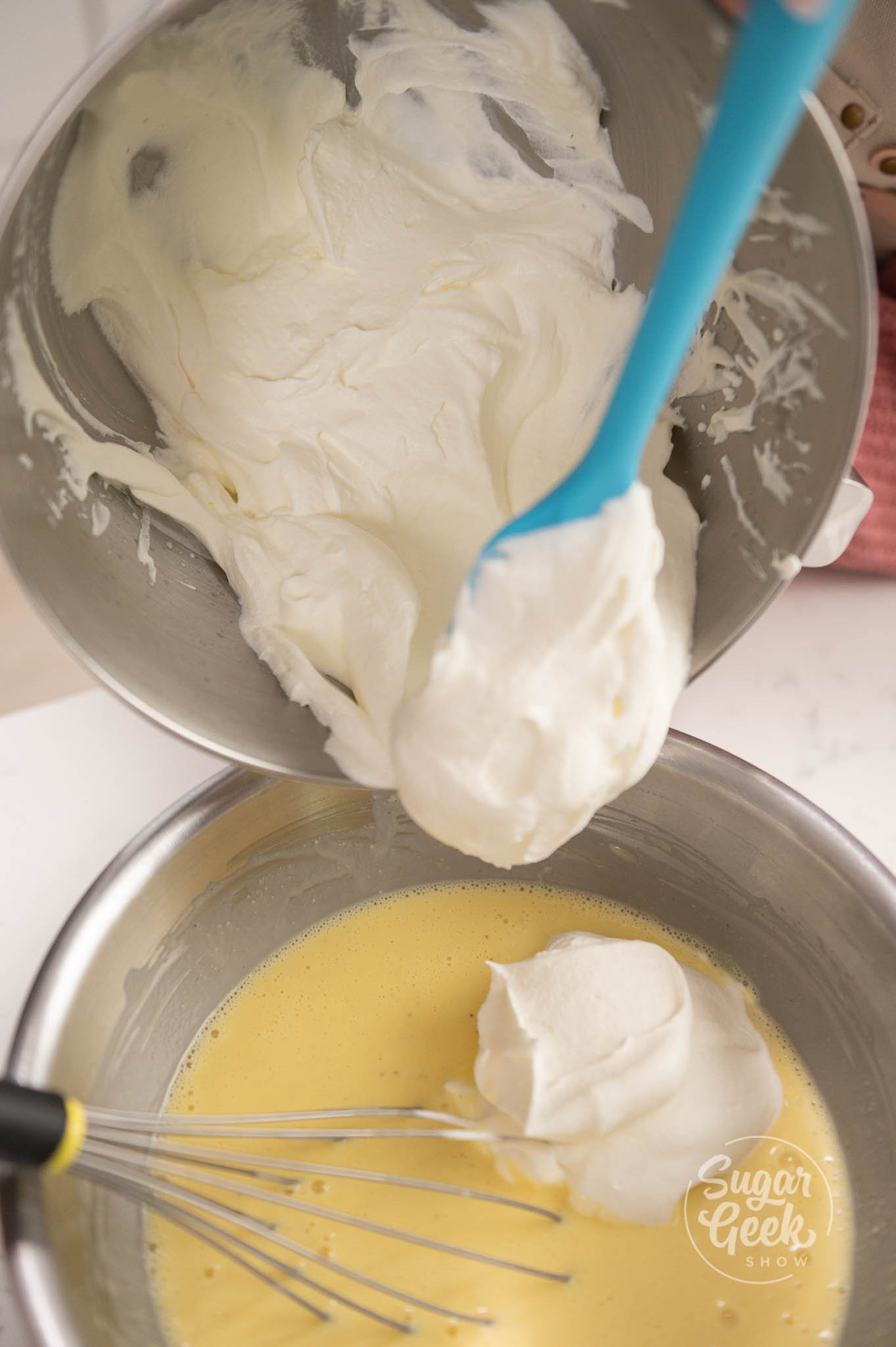 spoon scooping whipped cream into egg yolk mixture.